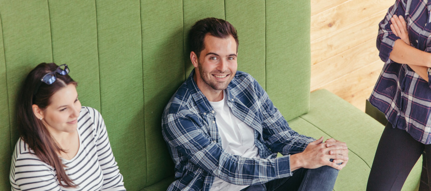Two professionals seated on a green sofa, engaged in a conversation about Microsoft training